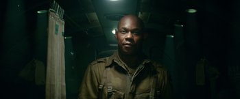 Movie still from “Overlord” (2018), directed by Julius Avery – A man in a military uniform standing in a dark room; Close Up shot, Low angle