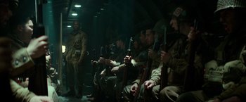 Movie still from “Overlord” (2018), directed by Julius Avery – A group of men sitting next to each other holding guns; Wide shot, Low angle