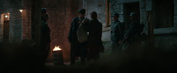 Movie still from “Overlord” (2018), directed by Julius Avery – A man and a woman are standing in front of a fire; Wide shot, Over the shoulder angle