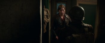 Movie still from “Overlord” (2018), directed by Julius Avery – A woman standing in front of an open door; Medium shot, Over the shoulder angle