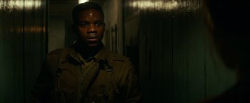Movie still from “Overlord” (2018), directed by Julius Avery – A man in a brown jacket standing next to a door; Close Up shot, High angle