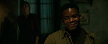 Movie still from “Overlord” (2018), directed by Julius Avery – A person smiling at the camera; Close Up shot, Over the shoulder angle