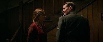 Movie still from “Overlord” (2018), directed by Julius Avery – A man and a woman standing next to each other in front of a staircase; Medium shot, Over the shoulder angle
