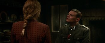 Movie still from “Overlord” (2018), directed by Julius Avery – A man in a military uniform looking at a woman in a red checkered shirt; Medium shot, Over the shoulder angle