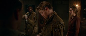 Movie still from “Overlord” (2018), directed by Julius Avery – A man in a military uniform looking down at his face; Medium shot, Over the shoulder angle