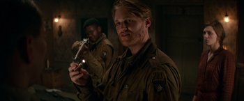 Movie still from “Overlord” (2018), directed by Julius Avery – A man holding a gun while standing next to another man; Medium shot, Over the shoulder angle