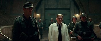 Movie still from “Overlord” (2018), directed by Julius Avery – A group of men standing next to each other in a building; Medium shot, Low angle