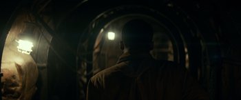 Movie still from “Overlord” (2018), directed by Julius Avery – A man standing in the dark looking at a light; Medium shot, Low angle