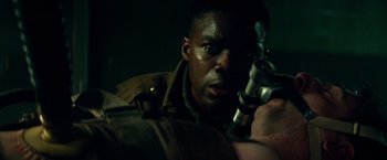 Movie still from “Overlord” (2018), directed by Julius Avery – A man holding a gun in a dark room; Close Up shot, Over the shoulder angle