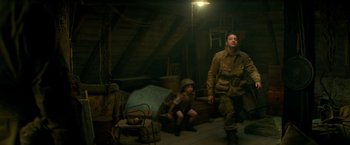 Movie still from “Overlord” (2018), directed by Julius Avery – A man and a boy in uniform in a room; Wide shot, Low angle