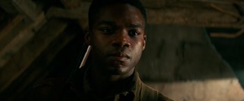 Movie still from “Overlord” (2018), directed by Julius Avery – A young man holding a cell phone in his ear; Close Up shot, Low angle