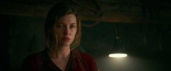 Movie still from “Overlord” (2018), directed by Julius Avery – A young woman is looking at the camera while standing in a dimly - lit room; Close Up shot, Low angle
