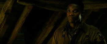 Movie still from “Overlord” (2018), directed by Julius Avery – A man standing in a dark room looking at the camera; Close Up shot, Low angle