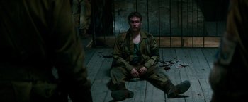 Movie still from “Overlord” (2018), directed by Julius Avery – A man sitting on the ground in a room; Medium shot, High angle