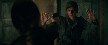 Movie still from “Overlord” (2018), directed by Julius Avery – A man holding a cell phone up to his face; Close Up shot, Over the shoulder angle