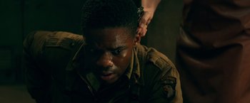 Movie still from “Overlord” (2018), directed by Julius Avery – A man in a military uniform is looking down at his ear; Close Up shot, High angle