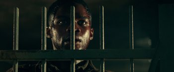 Movie still from “Overlord” (2018), directed by Julius Avery – A person behind a fence; Close Up shot, Low angle