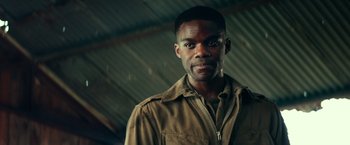 Movie still from “Overlord” (2018), directed by Julius Avery – A man wearing a brown shirt and a brown jacket; Close Up shot, Over the shoulder angle