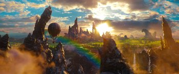 Movie still from “Oz the Great and Powerful” (2013), directed by Sam Raimi – A hot - air balloon flying over a mountain range at sunset; Extreme Wide shot, High angle
