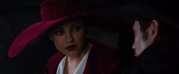 Movie still from “Oz the Great and Powerful” (2013), directed by Sam Raimi – A woman wearing a red hat and a white jacket; Close Up shot, Over the shoulder angle
