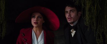Movie still from “Oz the Great and Powerful” (2013), directed by Sam Raimi – A man and a woman in a red hat and suit; Close Up shot, Low angle