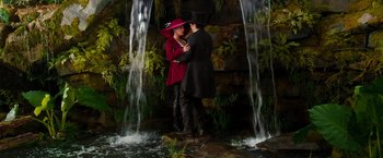 Movie still from “Oz the Great and Powerful” (2013), directed by Sam Raimi – A man and a woman standing in front of a waterfall; Wide shot, High angle
