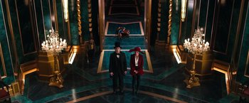 Movie still from “Oz the Great and Powerful” (2013), directed by Sam Raimi – Two people standing in a room with stairs; Wide shot, Overhead angle
