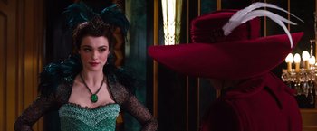 Movie still from “Oz the Great and Powerful” (2013), directed by Sam Raimi – A woman in a green dress and a red hat; Medium shot, Over the shoulder angle