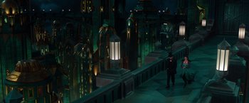 Movie still from “Oz the Great and Powerful” (2013), directed by Sam Raimi – A man standing next to a building at night time; Extreme Wide shot, High angle