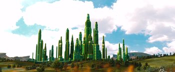Movie still from “Oz the Great and Powerful” (2013), directed by Sam Raimi – An image of a city with many trees in front of it; Extreme Wide shot, Low angle