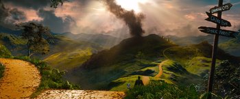 Movie still from “Oz the Great and Powerful” (2013), directed by Sam Raimi – A view of a mountain with a cloud of smoke coming out of it; Extreme Wide shot, High angle