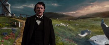 Movie still from “Oz the Great and Powerful” (2013), directed by Sam Raimi – A man standing in front of a grassy field; Medium shot, Low angle
