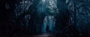 Movie still from “Oz the Great and Powerful” (2013), directed by Sam Raimi – A person standing in the middle of a dark forest; Extreme Wide shot, Low angle