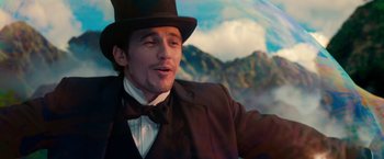 Movie still from “Oz the Great and Powerful” (2013), directed by Sam Raimi – A person wearing a suit and a top hat; Medium shot, Over the shoulder angle