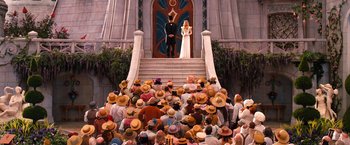 Movie still from “Oz the Great and Powerful” (2013), directed by Sam Raimi – A crowd of people sitting in front of a building; Wide shot, High angle