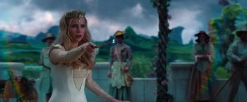 Movie still from “Oz the Great and Powerful” (2013), directed by Sam Raimi – A woman in a white dress holding a wand in front of a man; Medium shot, Over the shoulder angle