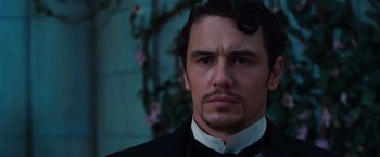 Movie still from “Oz the Great and Powerful” (2013), directed by Sam Raimi – A person wearing a suit and tie; Close Up shot, Over the shoulder angle