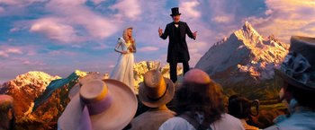 Movie still from “Oz the Great and Powerful” (2013), directed by Sam Raimi – A man and a woman are standing in front of a crowd; Medium shot, Low angle