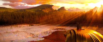 Movie still from “Oz the Great and Powerful” (2013), directed by Sam Raimi – The sun is setting over the mountains and the water; Extreme Wide shot, High angle