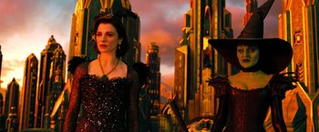 Movie still from “Oz the Great and Powerful” (2013), directed by Sam Raimi – A woman in a black dress standing in front of a city; Medium shot, Over the shoulder angle