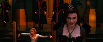 Movie still from “Oz the Great and Powerful” (2013), directed by Sam Raimi – Two women dressed up in costumes and one is wearing a feather crown; Medium shot, Over the shoulder angle