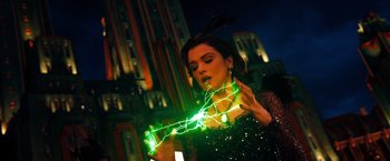 Movie still from “Oz the Great and Powerful” (2013), directed by Sam Raimi – A woman in a black dress is holding a green light; Medium shot, Over the shoulder angle