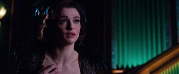Movie still from “Oz the Great and Powerful” (2013), directed by Sam Raimi – A woman in a black dress is standing in front of a green light; Close Up shot, Over the shoulder angle