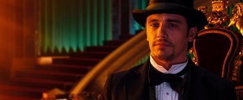Movie still from “Oz the Great and Powerful” (2013), directed by Sam Raimi – A man wearing a suit and a bow tie in front of a staircase; Close Up shot, Low angle