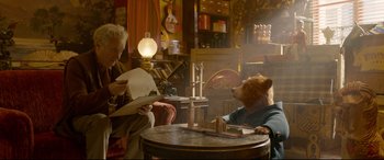 Movie still from “Paddington 2” (2017), directed by Paul King – A man sitting at a table next to a brown bear; Medium shot, Over the shoulder angle