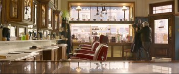 Movie still from “Paddington 2” (2017), directed by Paul King – A row of red chairs in front of a store window; Wide shot, Low angle