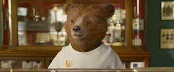 Movie still from “Paddington 2” (2017), directed by Paul King – A brown bear wearing a white t - shirt; Close Up shot, Low angle