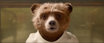 Movie still from “Paddington 2” (2017), directed by Paul King – A brown teddy bear wearing a white t - shirt; Close Up shot, Low angle