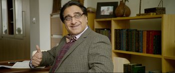 Movie still from “Paddington 2” (2017), directed by Paul King – A man in a suit and bow tie smiling for the camera; Medium shot, Over the shoulder angle