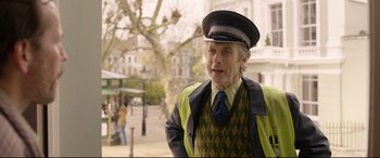 Movie still from “Paddington 2” (2017), directed by Paul King – An older man wearing a hat and a vest; Medium shot, Over the shoulder angle
